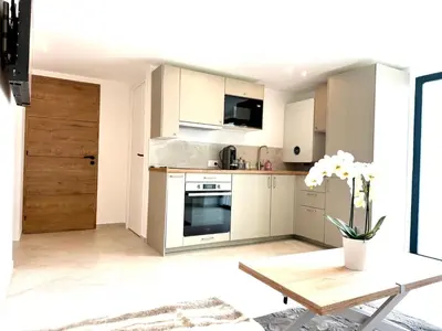 a small kitchen with white cabinets and a table at Appartment Jacuzzi in Cannes in Cannes