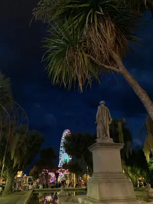 a statue in a park at night with a ferris wheel at RenTcik in Cannes