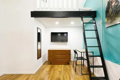 a loft bed in a room with a tv and a ladder at Little Garden YourHostHelper in Cannes