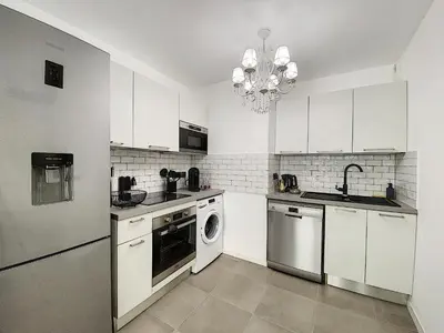 a kitchen with white cabinets and a washer and dryer at Apartment Palm Beach with a nice swimming pool in Cannes