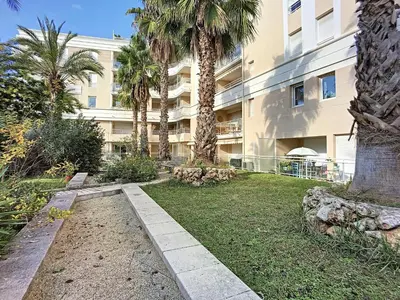 a building with palm trees in front of a yard at Nicolas 2 in Cannes