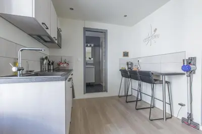 a kitchen with a sink and a counter with bar stools at LB Vacation Rentals I Cute Affordable 1-Br Minutes From Cannes Center in Cannes