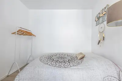 a white bedroom with a bed with a gray blanket at LB Vacation Rentals I Cute Affordable 1-Br Minutes From Cannes Center in Cannes