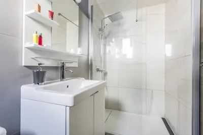 a white bathroom with a sink and a shower at LB Vacation Rentals I Cute Affordable 1-Br Minutes From Cannes Center in Cannes