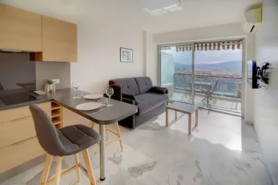 a kitchen and living room with a table and a couch at IMMOGROOM- Magnificent View - NEW - Terrace - AC in Cannes