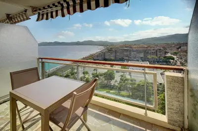 a balcony with a table and chairs and a view of the ocean at IMMOGROOM- Magnificent View - NEW - Terrace - AC in Cannes