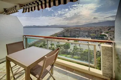 a balcony with a table and chairs and a view of the ocean at IMMOGROOM- Magnificent View - NEW - Terrace - AC in Cannes