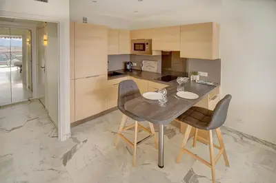a kitchen with a wooden table and two chairs at IMMOGROOM- Magnificent View - NEW - Terrace - AC in Cannes
