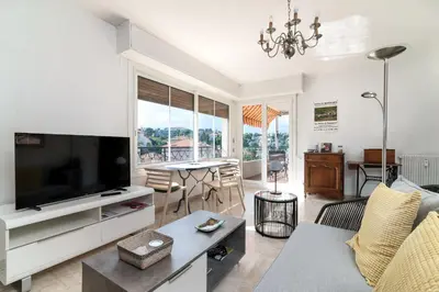 a living room with a television and a table with chairs at COPACABANA appartement 2 chambres in Cannes