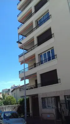 a building with balconies and a car parked in front of it at COPACABANA appartement 2 chambres in Cannes