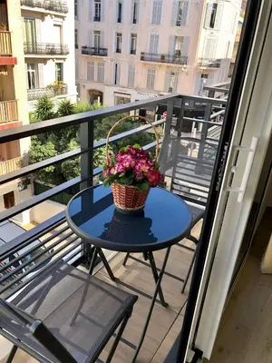 a table with a basket of flowers on a balcony at Brand new studio in the heart of Cannes in Cannes