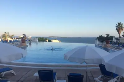 a swimming pool with chairs and umbrellas and the ocean at Sea views and beautiful pool in Cannes