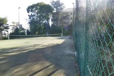 a tennis court with a fence and a tennis net at Sea views and beautiful pool in Cannes
