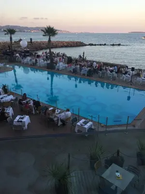 a large swimming pool with people sitting in chairs next to the water at Chambre spacieuse indépendante dans villa plus parking privée in Le Cannet