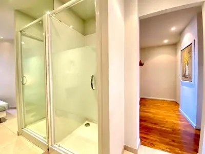 a glass shower stall in a room with wooden floors at Latour Maubourg By SCLS Locations in Cannes