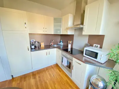 a kitchen with white cabinets and a microwave at Latour Maubourg By SCLS Locations in Cannes