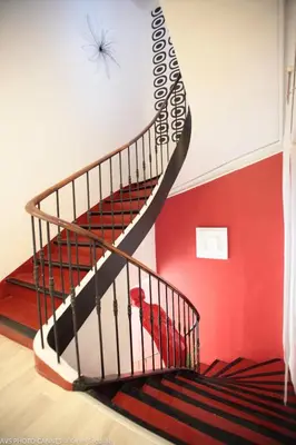a staircase with a red wall and a bird in a cage at O Carré Croisette Cannes in Cannes