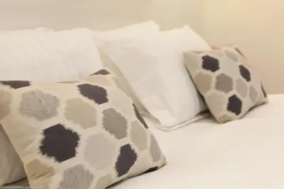 a bed with white pillows and brown and white pillows at O Carré Croisette Cannes in Cannes