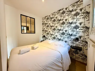 a bedroom with a bed with a palm wallpaper at C001-Beau studio neuf situé au centre in Cannes