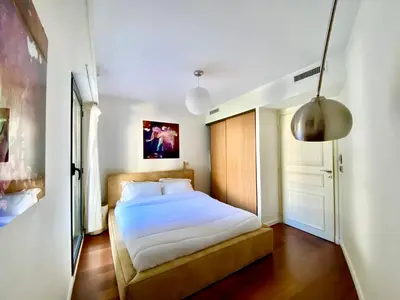 a bedroom with a white bed with a wooden floor at Carlton Riviera in Cannes