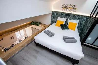 a bedroom with a large bed with yellow and black pillows at Duplex : Plage 300m, Clim, Netflix in Cannes