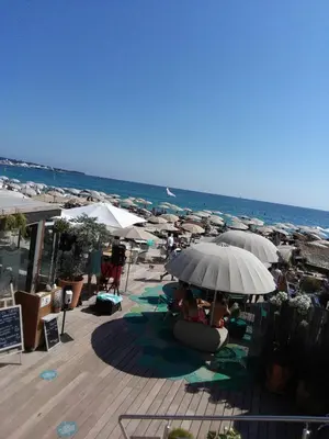 a group of people sitting under umbrellas on a beach at Gatsby Cannes Croisette in Cannes
