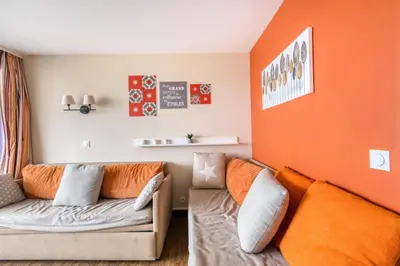 a living room with a couch and an orange wall at Résidence Cannes Villa Francia - maeva Home - Appartement 2 Pièces 6 Personnes - Sélection MAE-6133 in Cannes