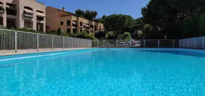 a large blue swimming pool in front of some buildings at Appartement de charme wi-fi ,clim, garage jardin privés, piscine environnement arboré in Cannes