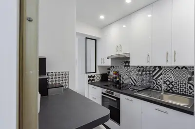 a kitchen with white cabinets and a black counter top at Cannes Palm Beach district 2 min to the beaches in Cannes