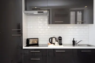 a kitchen with black cabinets and a counter top at C004-Cosy studio proche la Croisette et le Suquet in Cannes