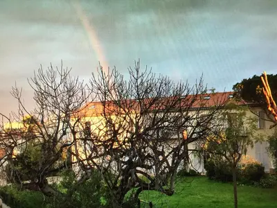 a rainbow in the sky over a house with a tree at Centre Ville Calme Festivales Plages in Cannes