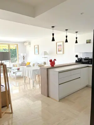 a kitchen with white cabinets and a living room at Solezia appartement, piscine et vue mer, by Welcome to Cannes in Cannes