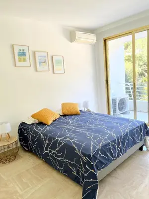 a bedroom with a bed with a blue comforter at Solezia appartement, piscine et vue mer, by Welcome to Cannes in Cannes