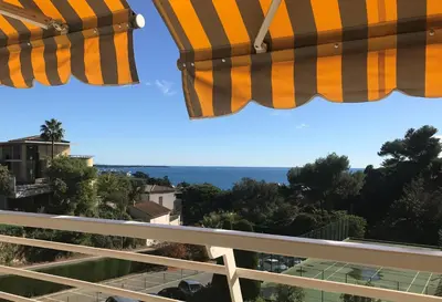 a view of the ocean from a balcony with umbrellas at Solezia appartement, piscine et vue mer, by Welcome to Cannes in Cannes