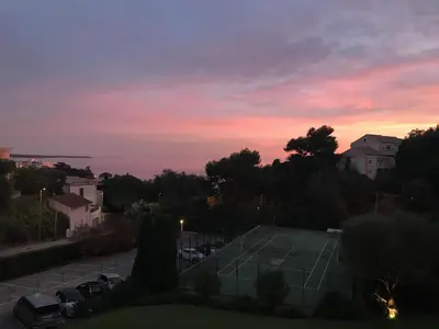 a tennis court in a parking lot at sunset at Solezia appartement, piscine et vue mer, by Welcome to Cannes in Cannes