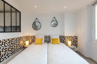 a bedroom with a white bed with two yellow pillows at Le Forville : 400m Palais, Calme, Clim in Cannes