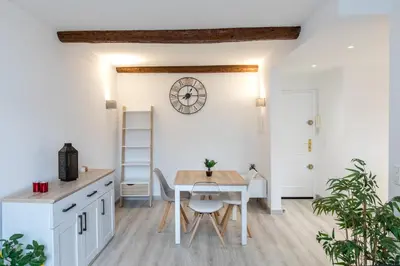 a kitchen and dining room with a table and a clock on the wall at Le Forville : 400m Palais, Calme, Clim in Cannes