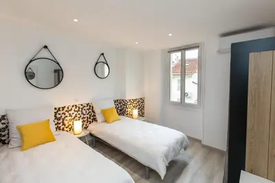 a bedroom with two beds and a mirror at Le Forville : 400m Palais, Calme, Clim in Cannes