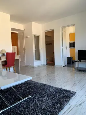 a living room with a white table and a red chair at Cannes Standing proche Croisette in Cannes
