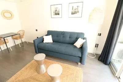 a living room with a blue couch and a table at Beautiful studio at the Grand Hotel Residence with sunny balcony 138 in Cannes