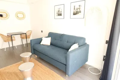 a blue couch in a living room with a table at Beautiful studio at the Grand Hotel Residence with sunny balcony 138 in Cannes