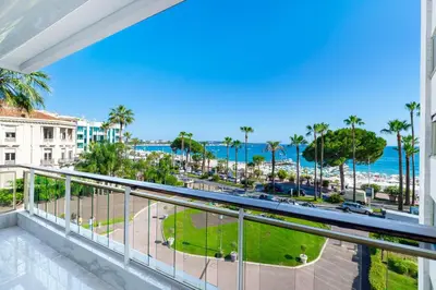 a balcony with a view of the beach and palm trees at Agence des Résidences - Appartements privés du 45 CROISETTE- Prestige in Cannes
