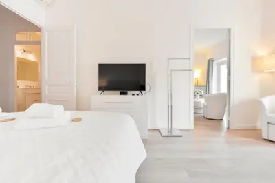 a white bedroom with a bed and a television at 2-Br City center near Croisette & Palais in Cannes