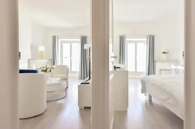 a white bedroom with a bed and a living room at 2-Br City center near Croisette & Palais in Cannes