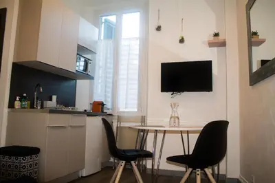 a kitchen with a table and chairs and a tv on the wall at Appartement palais plages in Cannes