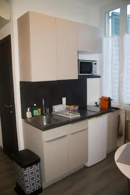a white kitchen with a sink and a microwave at Appartement palais plages in Cannes