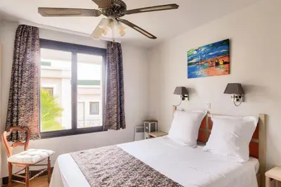a bedroom with a bed with a ceiling fan and a window at Résidence Cannes Villa Francia - maeva Home - Appartement 3 pièces 6 personnes - Sélection MAE-8432 in Cannes