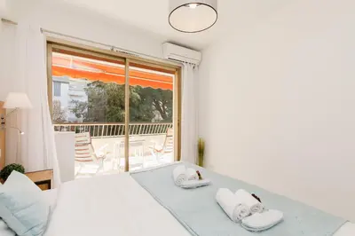 a white bedroom with a bed and a balcony at All Blue YourHostHelper in Cannes