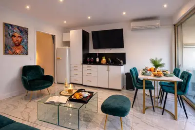 a kitchen and living room with a table and chairs at Luxury Maubourg - Vue mer - Croisette 50m plage - Clim - terrasse in Cannes
