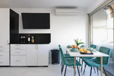 a kitchen with a table with green chairs and a television at Luxury Maubourg - Vue mer - Croisette 50m plage - Clim - terrasse in Cannes
